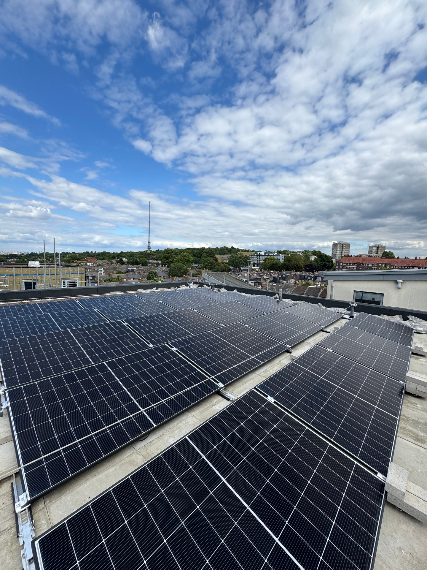 Flat-roof solar PV array on a multi-storey London development with skyline views