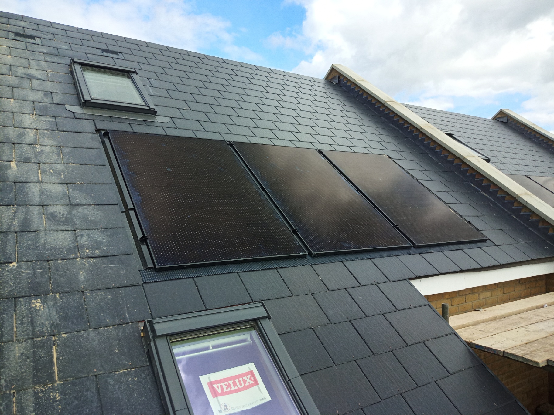 All-black solar PV panels on a slate pitched roof with Velux windows