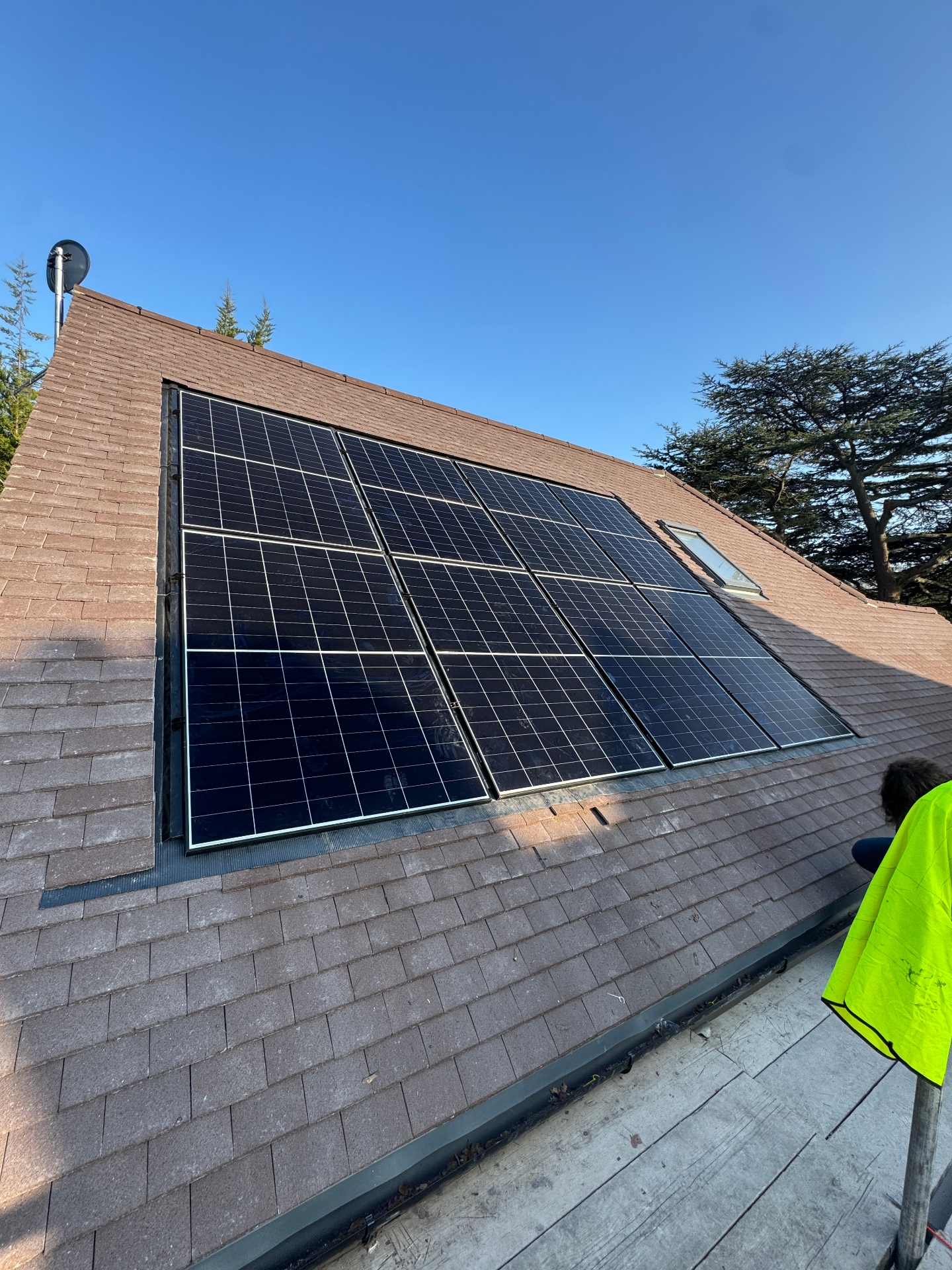 Solar PV array installed on a clay tile pitched roof beside a Velux window